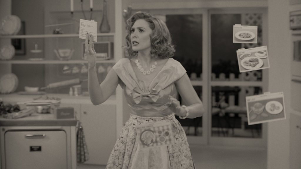 Elizabeth Olsen as Wanda Maximoff struggles to cook dinner with her magic powers in a 50s inspired black and white setting as seen in WandaVision.