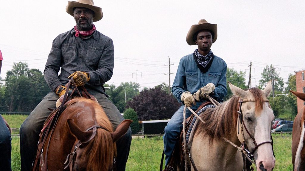 Idris Elba and Caleb McLaughlin riding horses in cowboy attire as seen in Concrete Cowboy directed by Ricky Staub.