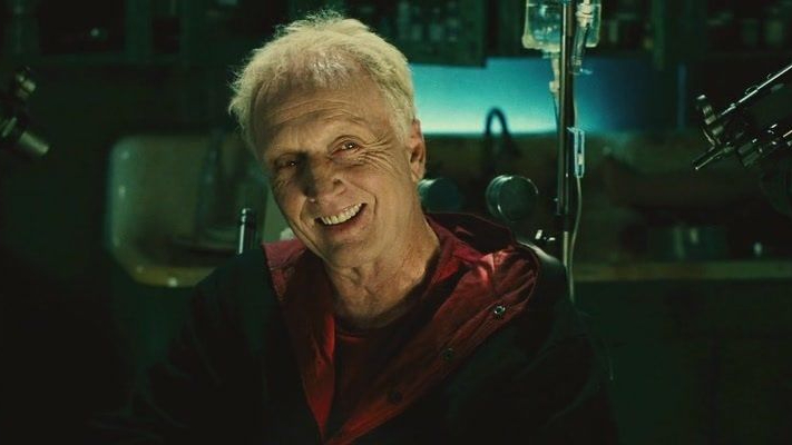 Tobin Bell as John Kramer aka Jigsaw smirking with guns up to his face as seen in Saw II.