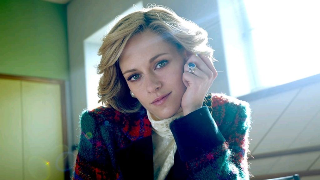 Kristen Stewart as Princess Diana tilting her head and starring into the camera as the sun shines on her face as seen in SPENCER directed by Pablo Larraín.