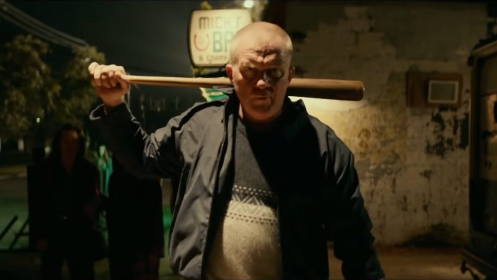 Anthony Michael Hall as Tommy Doyle leads a mob while holding a baseball bat over his shoulders as seen in HALLOWEEN KILLS directed by David Gordon Green.