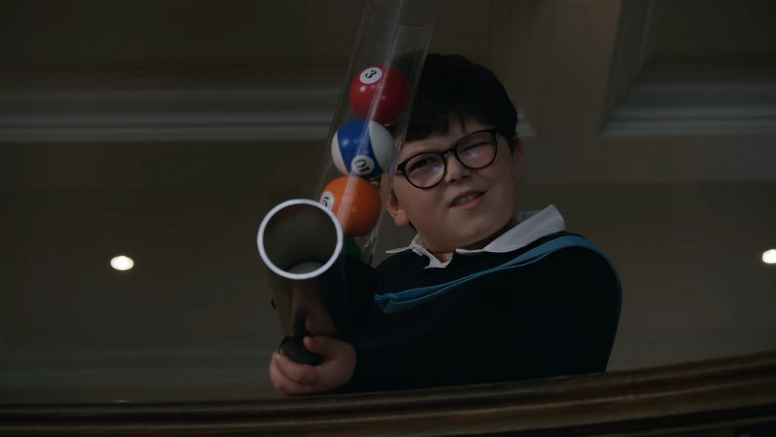 Archie Yates as mischievous young Max mercer firing a gun loaded with colorful billiards balls in the new Disney+ Home Alone sequel HOME SWEET HOME ALONE directed by Dan Mazer.