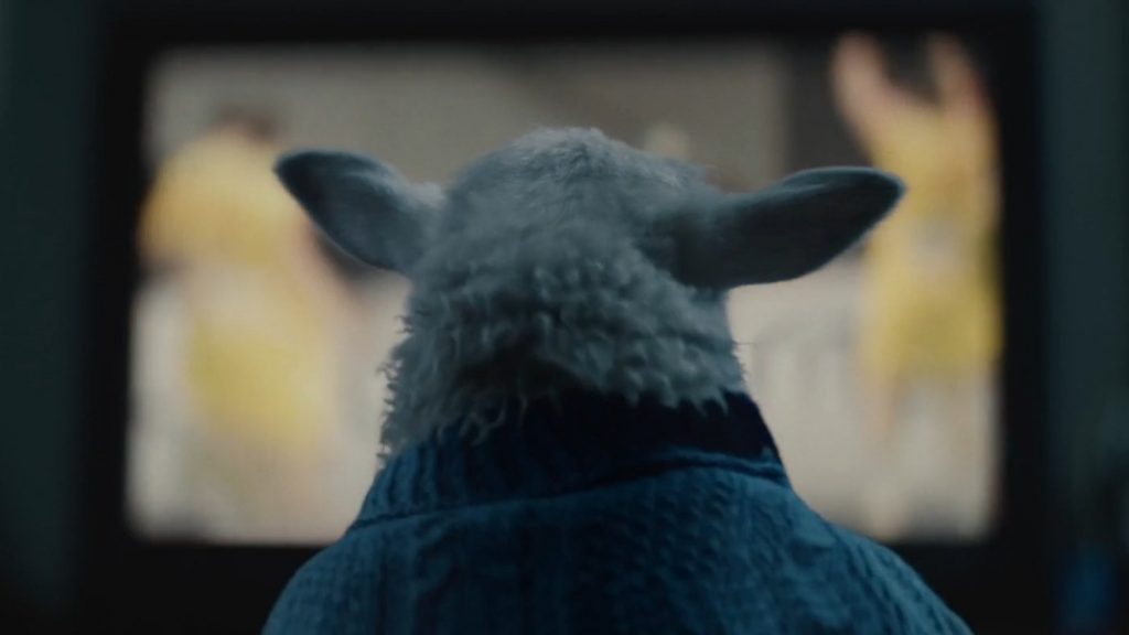 Ada the half-human, half-sheep hybrid child sits in front of a TV and watches sports in curiosity as seen in the A24 film LAMB directed by Valdimar Jóhannsson and starring Noomi Rapace.