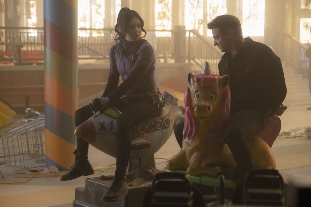 Kate Bishop played by Hailee Steinfeld and Clint Barton played by Jeremy Renner are tied hostage together on some old carnival rides as seen in Episode 3 of HAWKEYE on Disney+