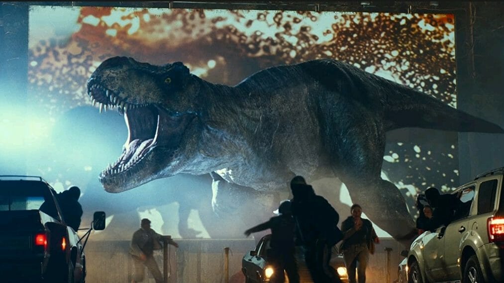 The iconic Tyrannosaurs Rex roars and wreaks havoc in front of a drive-in movie theater in the 2022 film JURASSIC WORLD DOMINION.