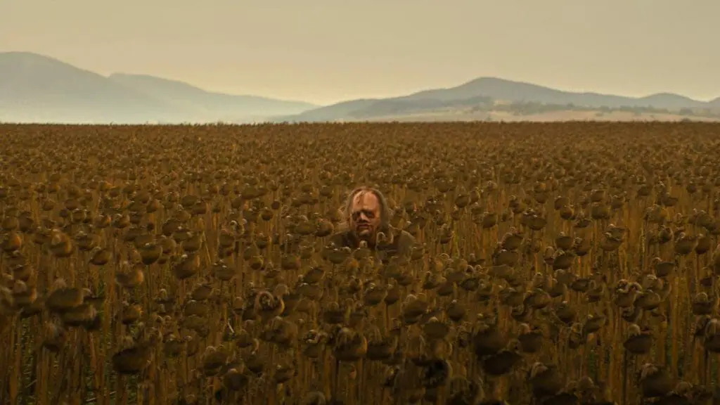 Leatherface stands in the middle of a tall wheat field as seen in the new TEXAS CHAINSAW MASSACRE coming to Netflix in February 2022.