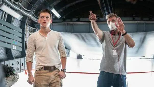 Director Ruben Fleischer blocks a scene with Tom Holland in costume as Nathan Drake on a cargo plane from the set of UNCHARTED, based on the iconic video game series from Naughty Dog.