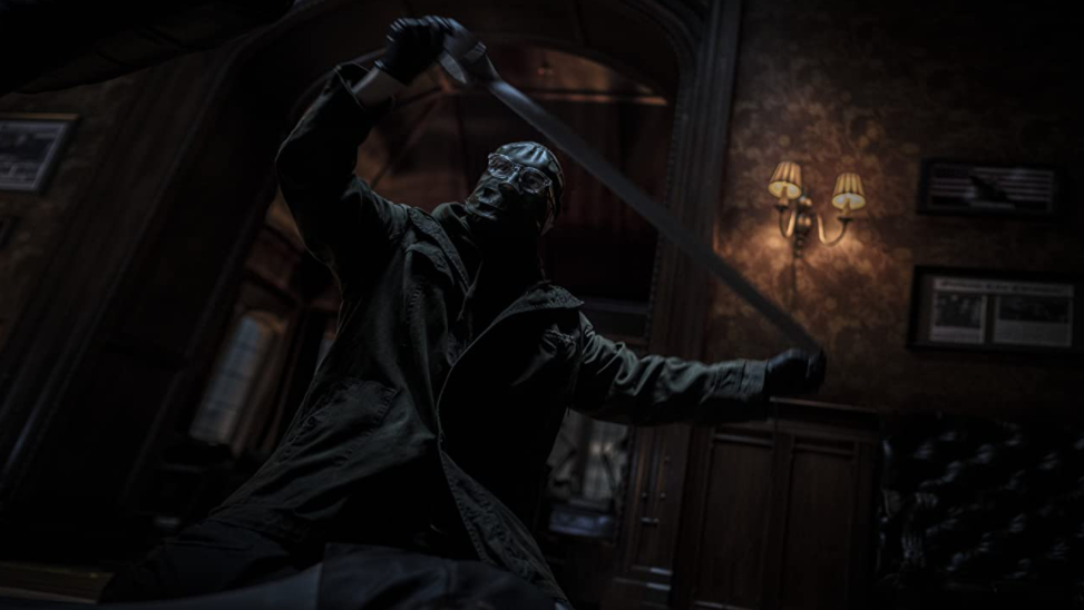 The Riddler played by Paul Dano stretches duct tape as he prepares to wrap a dead body as seen in THE BATMAN directed by Matt Reeves and produced by Dylan Clark.