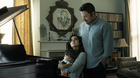 Ben Affleck and Ana de Armas pose as the perfect family while holding a baby by their living room piano as seen in the erotic thriller DEEP WATER on Hulu.