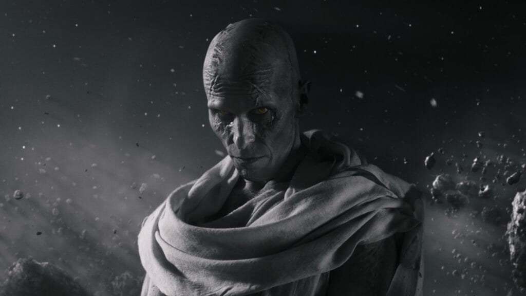Gorr the God Butcher played by Christian Bale stands menacingly in the black and white phantom zone with a sinister stare and piercing eyes in THOR: LOVE & THUNDER.