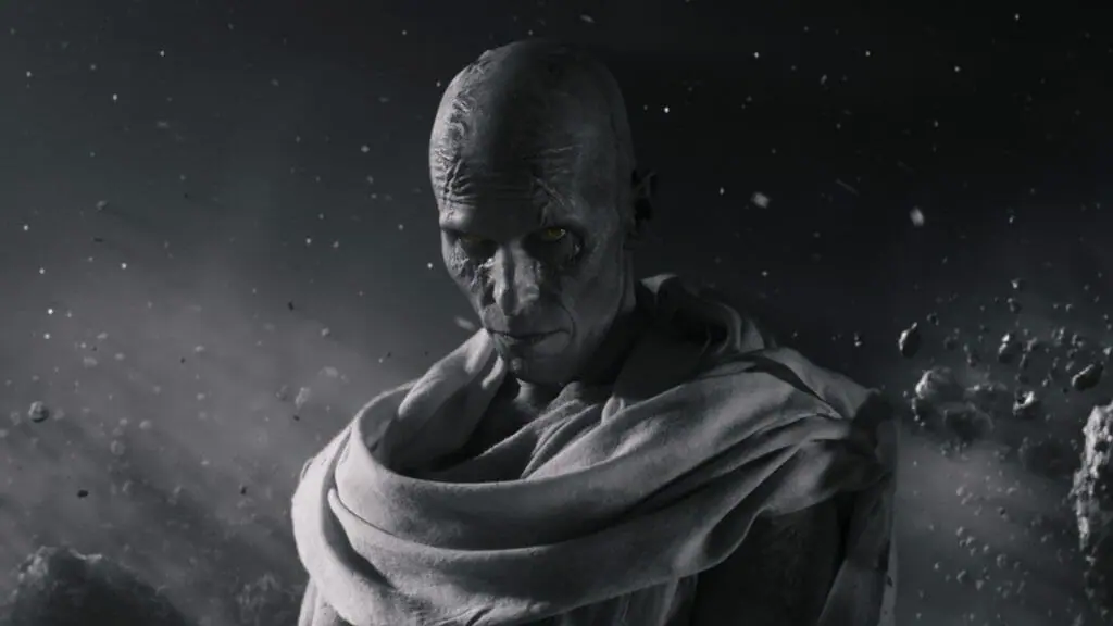 Gorr the God Butcher played by Christian Bale stands menacingly in the black and white phantom zone with a sinister stare and piercing eyes in THOR: LOVE & THUNDER.