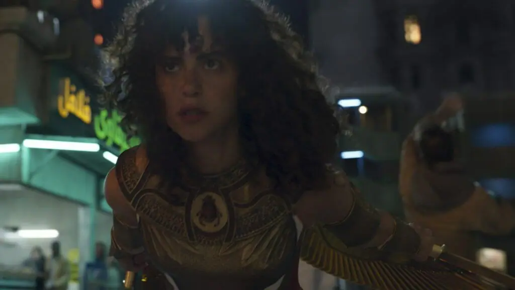 May Calamawy as the Scarlet Scarab shows off her shiny new armored suit in a battle pose while taking out enemies with her sharp golden dual swords in the Marvel series MOON KNIGHT on Disney+.