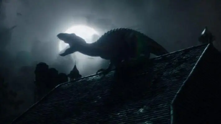 The horrific Indoraptor hybrid roars on top of a Gothic mansion in front of a bright full moon in an epic money shot from JURASSIC WORLD: FALLEN KINGDOM directed by J.A. Bayona.