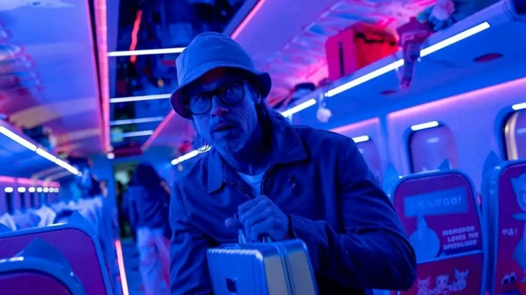 Codename "Ladybug" played by Brad Pitt steals a secret silver briefcase and tries to escape a train cart filled with passengers and bright purple neon lighting in BULLET TRAIN.