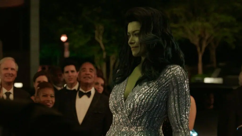 She-Hulk played by Tatiana Maslany walks the red carpet in a stunning silver dress as the crowd looks upon her in awe in the Disney+ MCU series SHE-HULK: ATTORNEY AT LAW.
