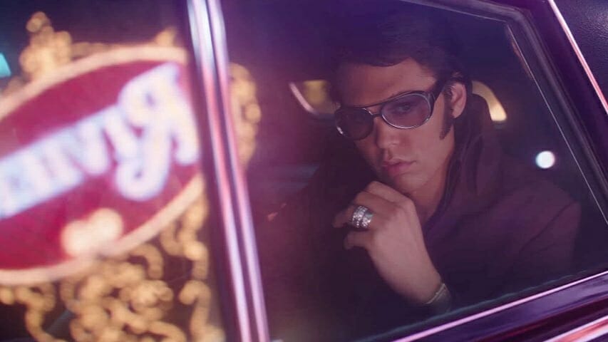 Austin Butler as Elvis Presley looks out the window while wearing huge sunglasses and driving down the Las Vegas strip in the movie directed by Baz Luhrmann now streaming on HBO Max in September 2022.