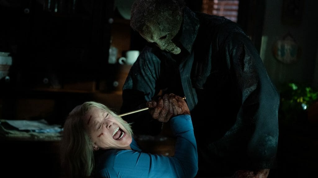 Michael Myers holds down Laurie Strode and presses a huge knitting needle against her face during their final horrifying battle in HALLOWEEN ENDS.