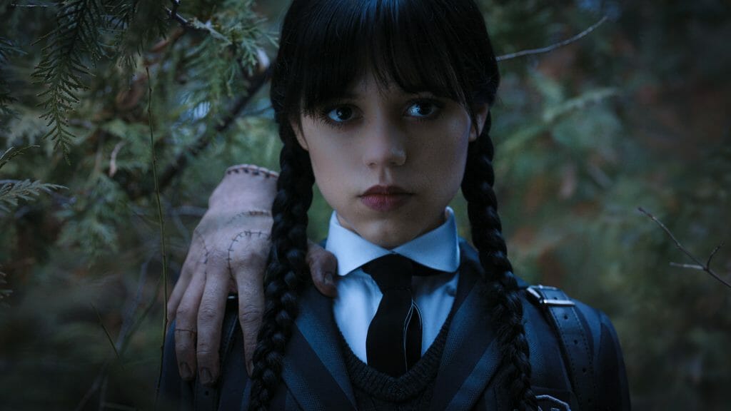 New Arrivals for Netflix November 2022 Jenna Ortega as Wednesday Addams strikes a brooding pose with the Thing severed hand on her shoulders in the new series coming to Netflix in November 2022.