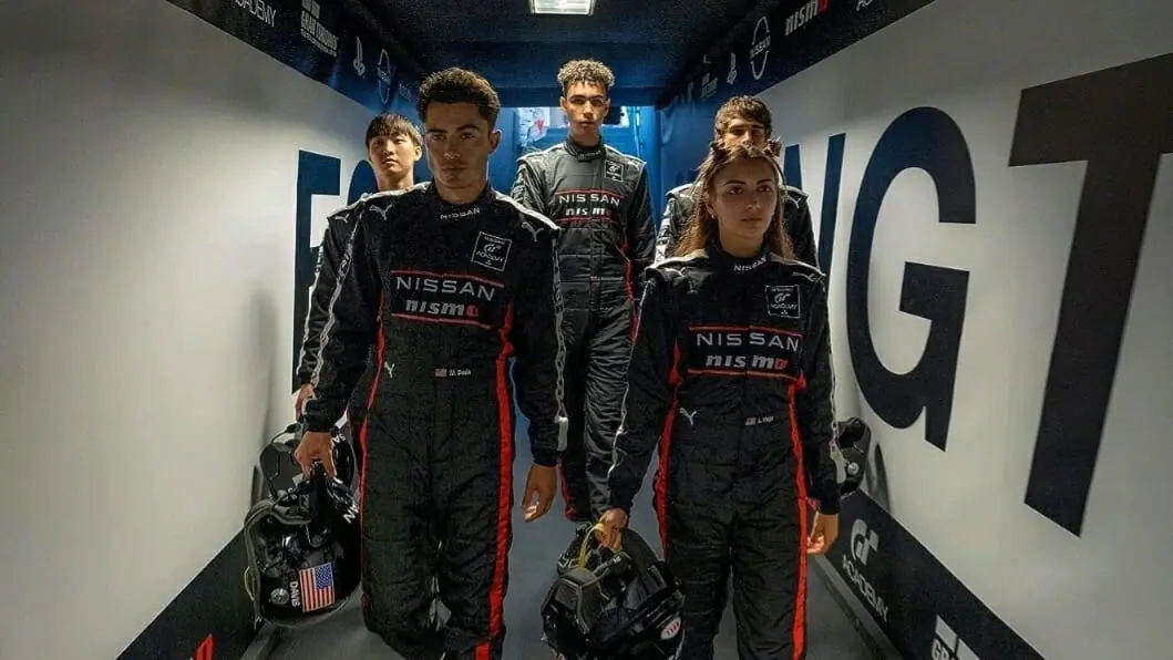 Sang Heon Lee, Josha Stradowski, Archie Madekwe, Darren Barnet, and Emelia Hartford walk down a hallway together in black Nissan GT uniforms in the GRAN TURISMO movie.