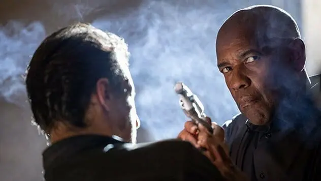 Denzel Washington as Robert McCall holds back a mobster from shooting him with a small gun during an intense action scene in THE EQUALIZER 3.