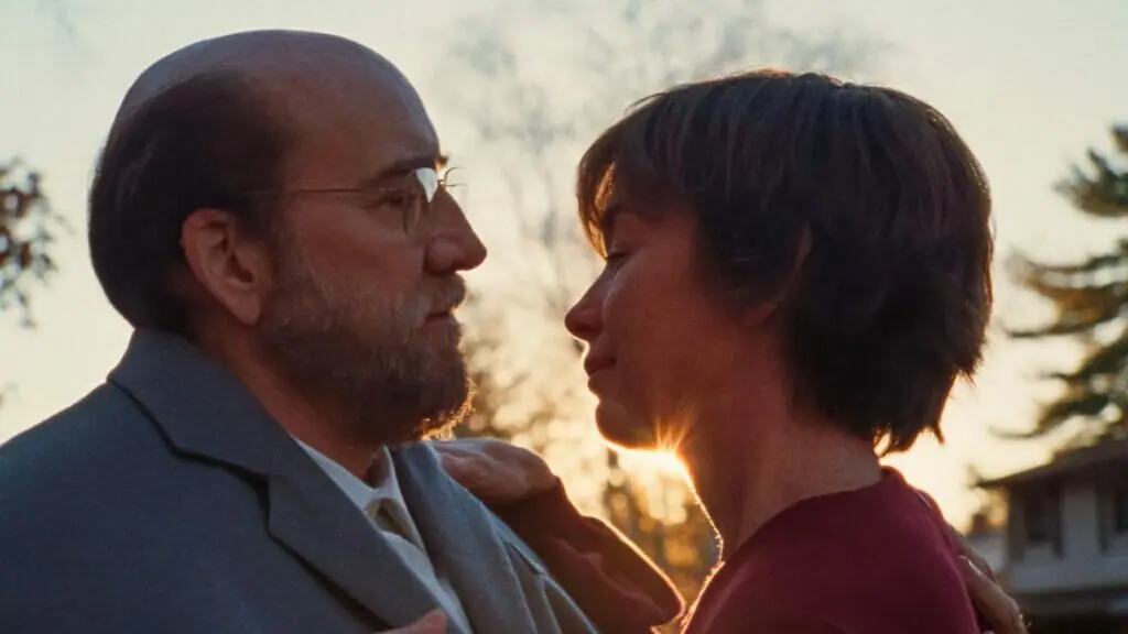Nicolas Cage is bald and has a beard as the main character Paul Matthews as he embraces his wife Janet played by Julianne Nicholson in the new A24 movie DREAM SCENARIO.