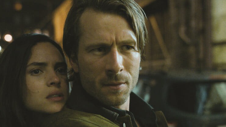 Adria Arjona and Glen Powell pose together in a cool action shot from the movie HIT MAN directed by Richard Linklater.