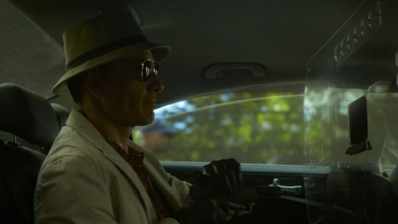 Michael Fassbender as the main nameless assassin loads a gun in the back of a taxi in the Netflix movie THE KILLER.