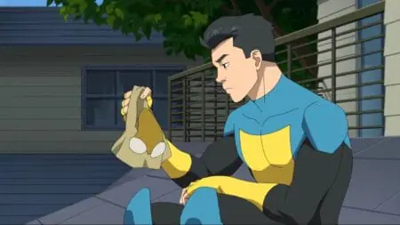Mark Grayson voiced by Steven Yeun sits on his rooftop in his Invincible superhero costume with his mask off in INVINCIBLE Season 2 streaming on Prime Video.