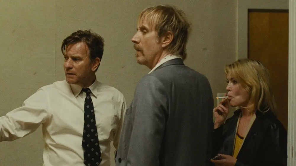 Ewan McGregor, Rhys Ifans, and Lara Flynn Boyle star as three adult siblings looking distressed in a furniture store in the family drama film MOTHER, COUCH. 