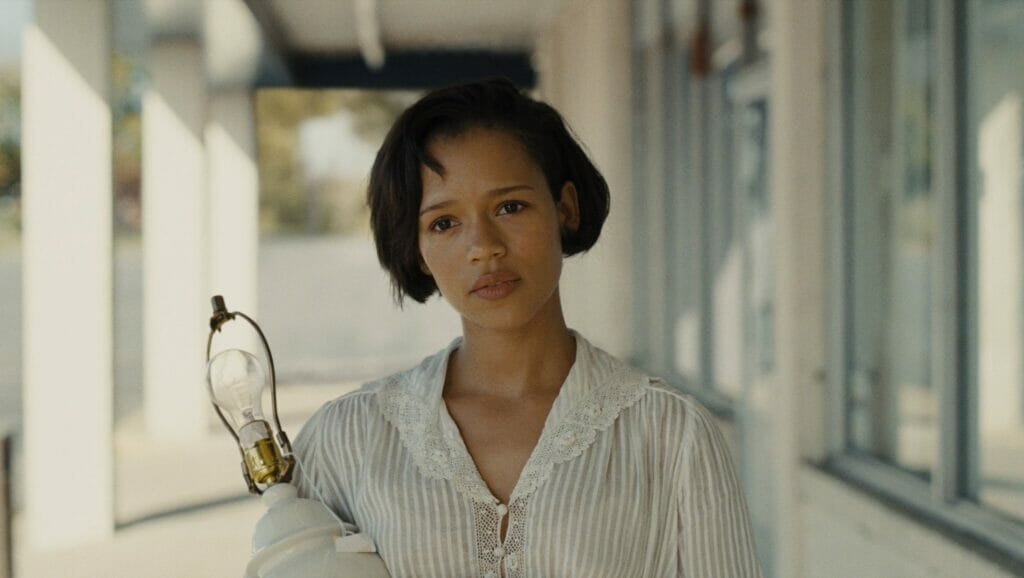 Taylor Russell stars as the young furniture store worker Bella holding a lamp in the family drama film MOTHER, COUCH. 