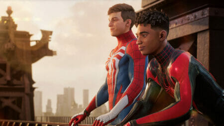 Peter Parker and Miles Morales stand together on a rooftop and look over New York City in their signature Spider-Man costumes with their masks off in MARVEL'S SPIDER-MAN 2 only on PlayStation 5.