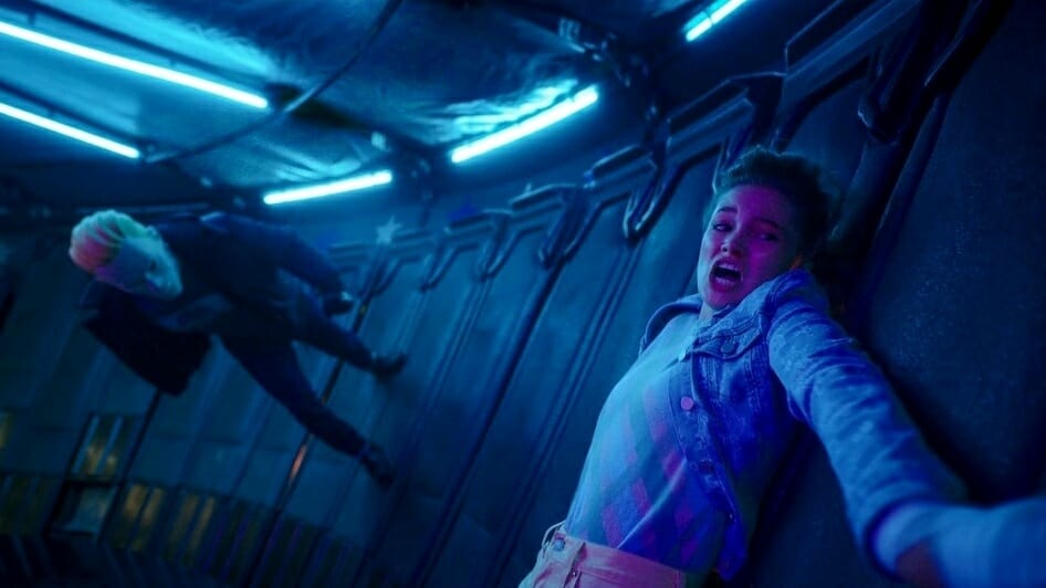 The masked Sweet Sixteen Killer chases after a helpless Olivia Holt who's stuck to a wall inside a Gravitron carnival ride in the horror comedy TOTALLY KILLER streaming on Amazon Prime Video.