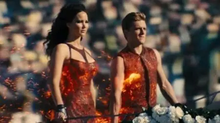 Katniss Everdeen and Peeta Melark show off their fire costumes during the opening Hunger Games ceremony, which makes our list of the 10 most iconic moments from the franchise.