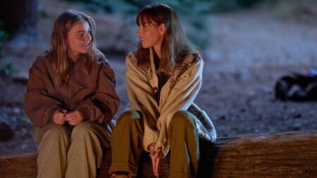 The young Maisy Stella meets the older 39-year-old version of herself played by Aubrey Plaza as the two sit cozy next to each other on a log in front of a camp fire in the movie MY OLD ASS.
