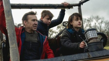 Nicolas Cage, Maxwell Jenkins, and Jaeden Martell ride in a large heavy-duty vehicle together in a post-apocalyptic setting in the action horror film ARCADIAN.