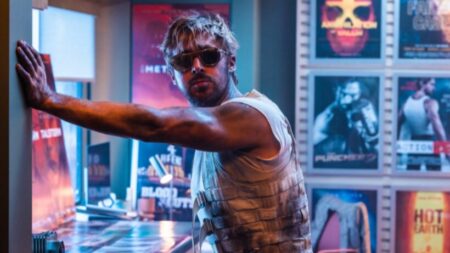 Ryan Gosling strikes a cool pose as stuntman Colt Seavers wearing sunglasses and a cable vest in the action rom-com THE FALL GUY.