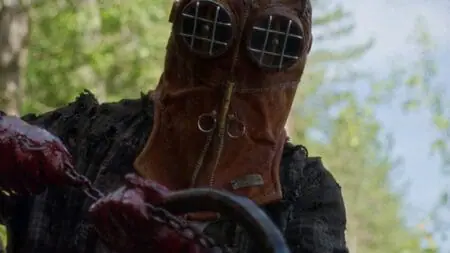 Johnny the main killer in the indie horror movie IN A VIOLENT NATURE wears an old firefighter helmet as he holds up a giant hook.