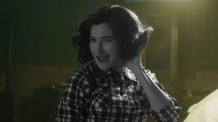 Kathryn Hahn stars as the powerful witch Agatha Harkness striking a hilarious pose as she holds her hand up to her ear in the Disney+ original series AGATHA ALL ALONG.