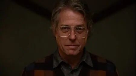 A close-up shot of Hugh Grant wearing large glasses and creepily starring into the camera as the devilish villain Mr. Reed from the A24 horror movie HERETIC.
