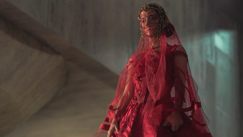 Sarah-Sofie Boussnina stars as Princess Ynez wearing a futuristic, lavish red wedding dress with a veil that covers her face in the HBO prequel series DUNE: PROPHECY.