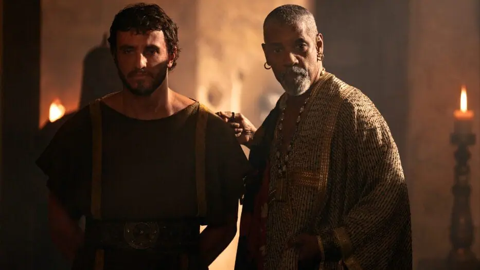 Macrinus, played by Denzel Washington, presents his gladiator Lucius, played by Paul Mescal, in shackles in the legacy sequel GLADIATOR II. 