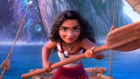 Moana voiced by Auliʻi Cravalho strikes an epic action pose holding her wayfinder oar while a giant ocean clam monster rises above the water behind her in the Disney sequel MOANA 2.