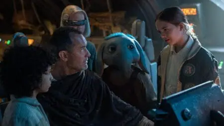 Jude Law as the mysterious force user Jod Na Nawood huddles up with a group of kids, including a blue elephant alien boy, on the cockpit of his spaceship in the new Disney+ series STAR WARS: SKELETON CREW.
