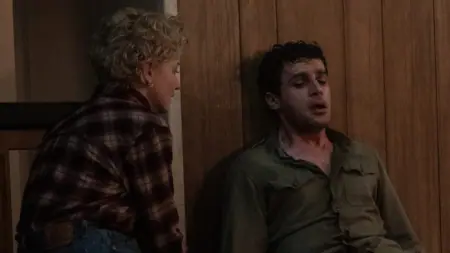 Christopher Abbott shivers and sweats heavily on the floor as his werewolf infection takes over while his wife played by Julia Garner tries to tend to him in the 2025 WOLF MAN movie.