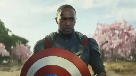 Anthony Mackie holds up the iconic red, white, and blue Captain America shield in the middle of a park with cherry blossom trees in Washington, D.C. in CAPTAIN AMERICA: BRAVE NEW WORLD.