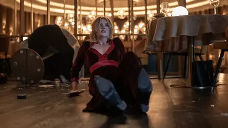Meghann Fahy as main character Violet crawls backwards on the floor of a thrashed fancy restaurant while looking absolutely horrified in the Blumhouse thriller movie DROP directed by Christopher Landon.