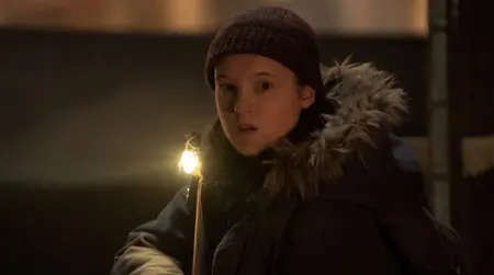 Bella Ramsey returns as Ellie Williams wearing winter gear and aiming an assault rifle in THE LAST OF US Season 2 which is included in the HBO and Max April 2025 list of new movies and TV shows.