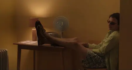 Troubled young homeless man Mike, played by Frank Dillane, looks all sluggish as he lays back on a chair against a yellow mustard colored wall in the drama movie URCHIN written and directed by Harris Dickinson.