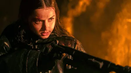 Ana de Armas stars as the assassin Eve Macarro holding up a large flamethrower in the John Wick spin-off movie BALLERINA.