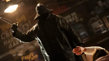 The iconic Fisherman killer in a black raincoat raises a large fish hook as he prepares to slash his next victim in the horror legacy sequel I KNOW WHAT YOU DID LAST SUMMER (2025).